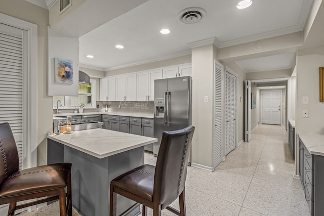 kitchen with stainless steel refrigerator with ice dispenser, baseboards, visible vents, and light speckled floor