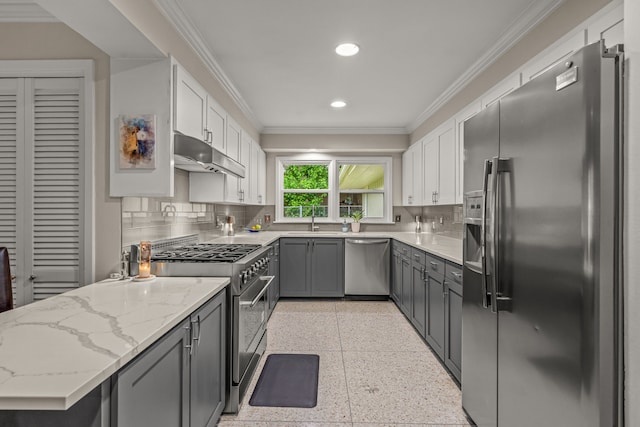 kitchen with appliances with stainless steel finishes, a sink, light speckled floor, under cabinet range hood, and ornamental molding