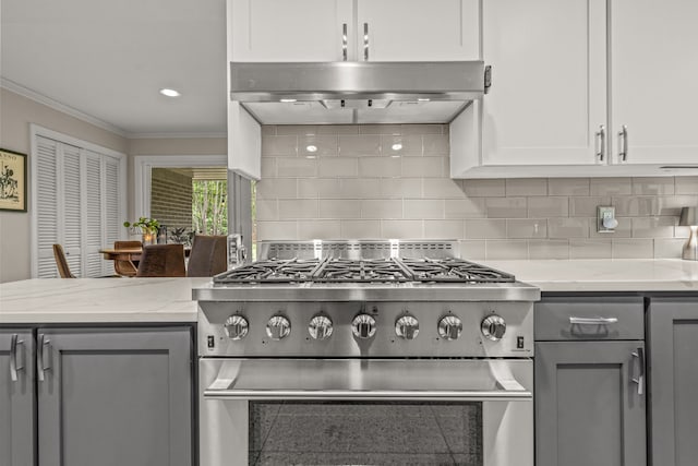 kitchen featuring crown molding, high end stainless steel range, extractor fan, light stone counters, and gray cabinetry