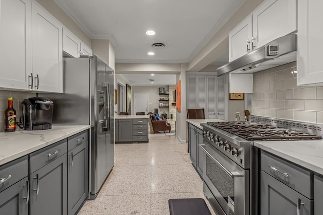 kitchen featuring ornamental molding, light speckled floor, backsplash, gray cabinetry, and stainless steel appliances