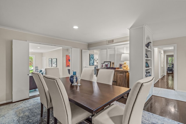 dining area with visible vents, ornamental molding, a wealth of natural light, and wood finished floors