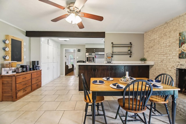 dining room featuring crown molding, a ceiling fan, brick wall, and light tile patterned floors