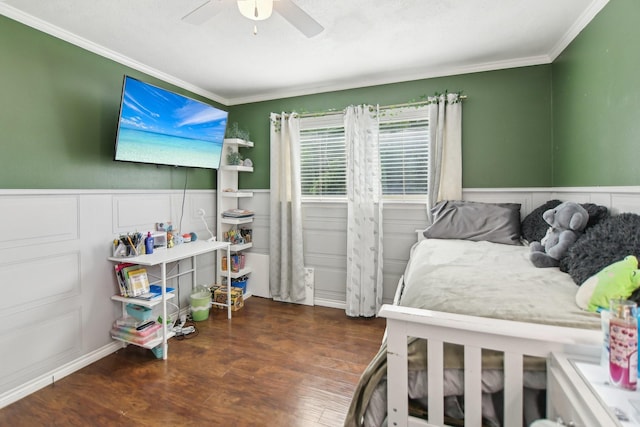 bedroom with wood finished floors, a wainscoted wall, ceiling fan, and ornamental molding