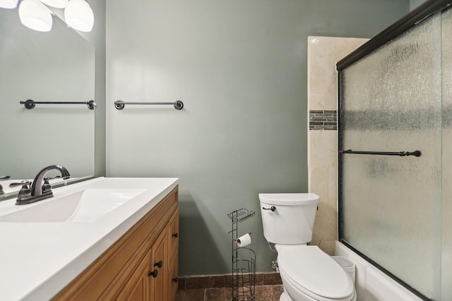 bathroom featuring combined bath / shower with glass door, vanity, baseboards, toilet, and tile patterned flooring