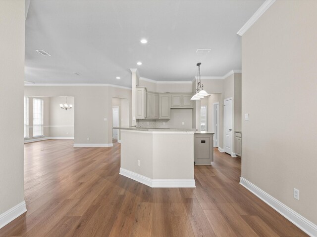 kitchen with a center island, ornamental molding, light countertops, baseboards, and a notable chandelier