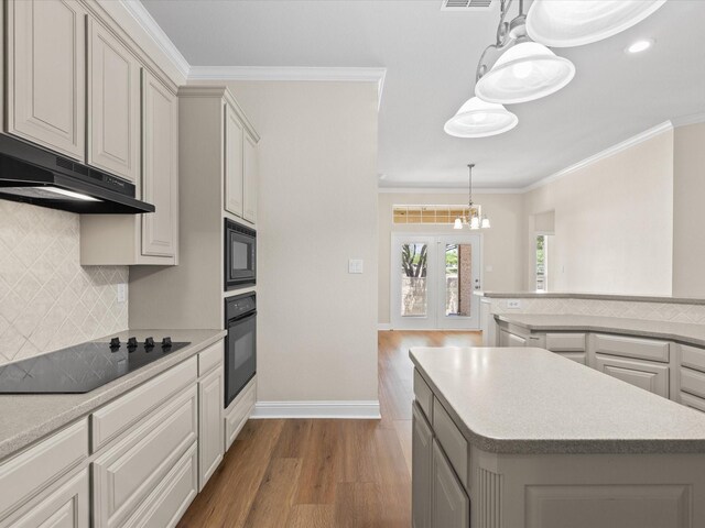 kitchen featuring under cabinet range hood, an inviting chandelier, light countertops, wood finished floors, and black appliances