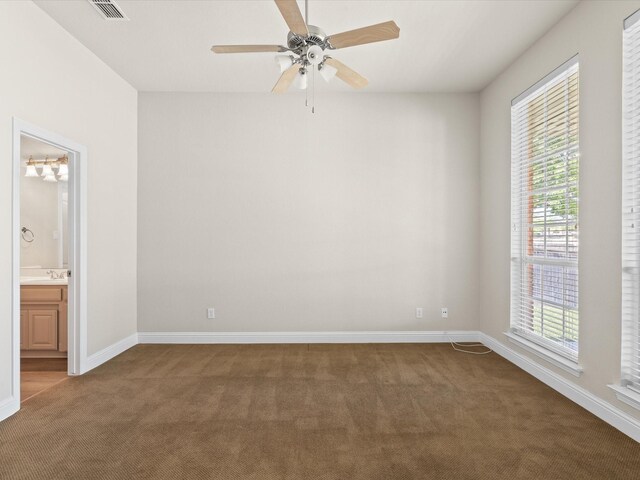 carpeted spare room with baseboards, visible vents, and ceiling fan