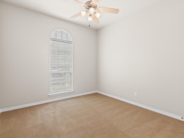 unfurnished room with ceiling fan, light carpet, and baseboards