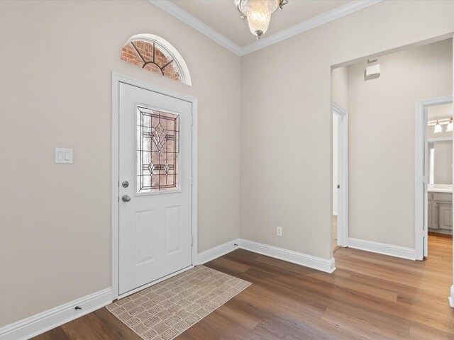 foyer entrance with baseboards, wood finished floors, and ornamental molding