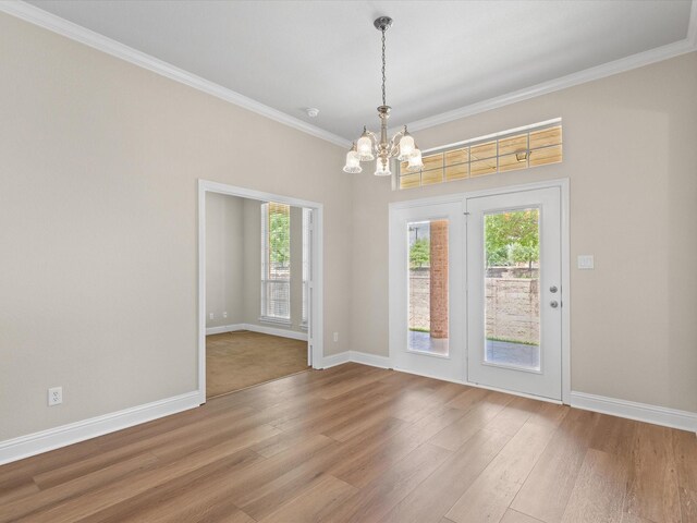 interior space with baseboards, crown molding, wood finished floors, and a chandelier
