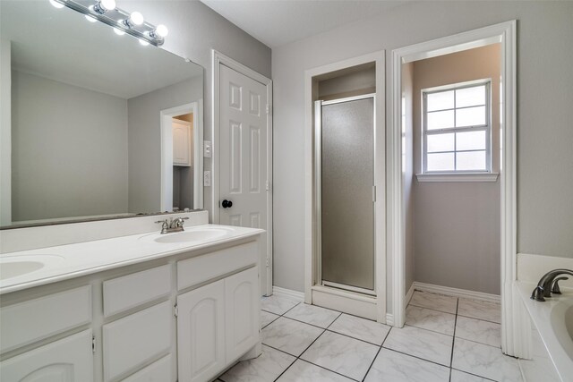 bathroom with a garden tub, a sink, a stall shower, marble finish floor, and double vanity