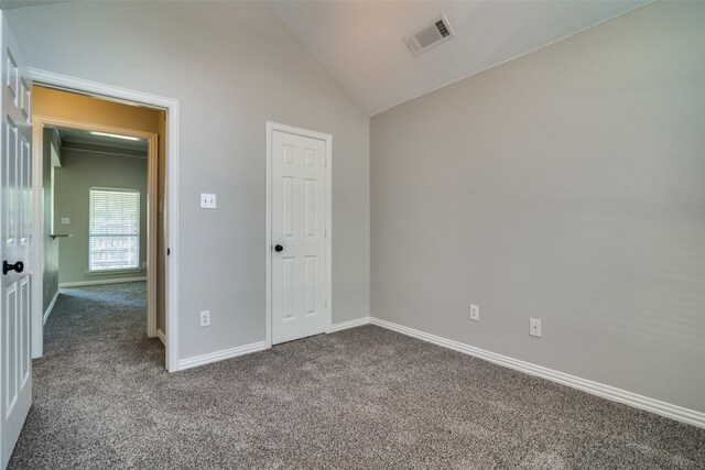 unfurnished bedroom featuring baseboards, dark colored carpet, visible vents, and vaulted ceiling