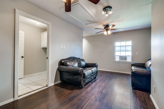 living area featuring attic access, a ceiling fan, wood finished floors, and baseboards