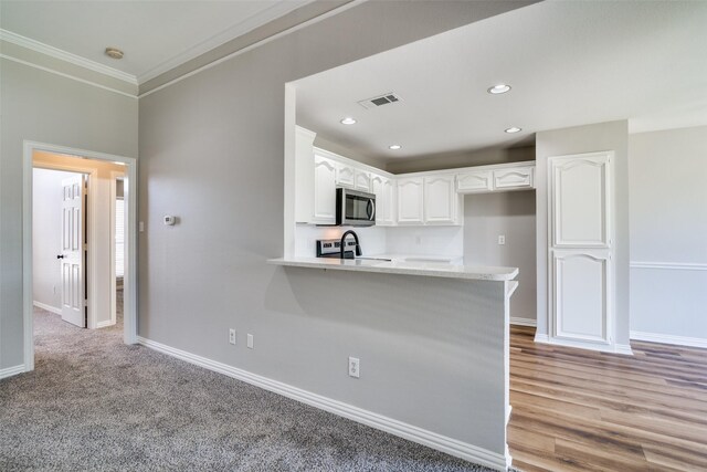 kitchen featuring crown molding, stainless steel appliances, a peninsula, white cabinetry, and visible vents