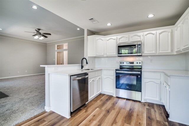 kitchen with a sink, stainless steel appliances, backsplash, a peninsula, and visible vents