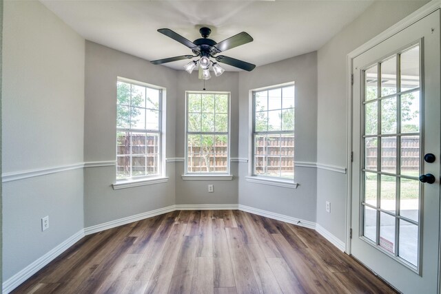 unfurnished room with baseboards, dark wood-style flooring, and a healthy amount of sunlight