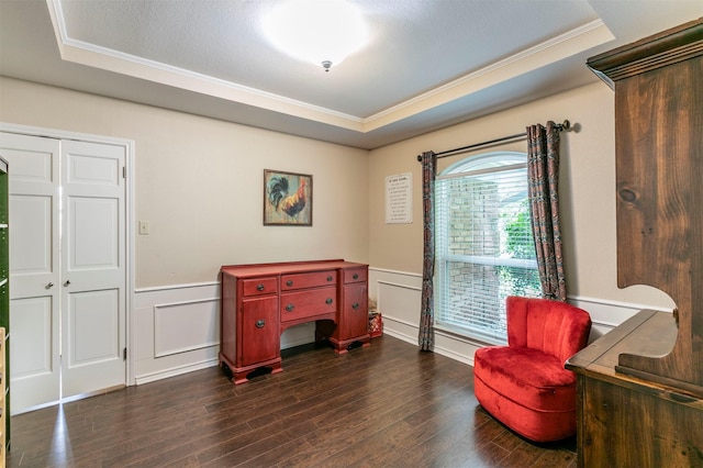sitting room with dark wood finished floors, ornamental molding, and a raised ceiling