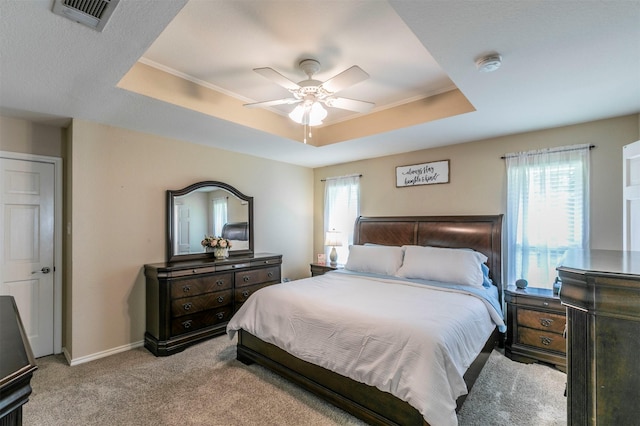 carpeted bedroom featuring baseboards, a ceiling fan, a tray ceiling, and visible vents