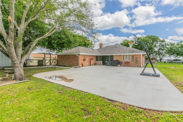 back of house with a chimney, brick siding, a yard, and a patio
