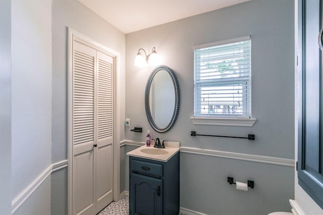 half bath with toilet, vanity, and baseboards