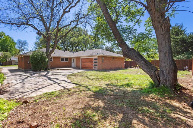exterior space with fence, brick siding, a garage, and concrete driveway