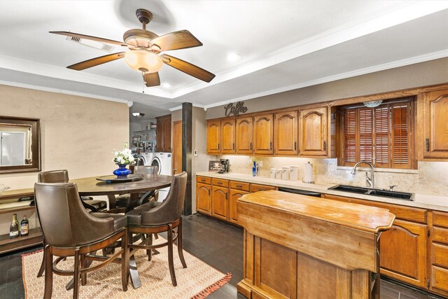 kitchen featuring brown cabinetry, ornamental molding, a sink, and separate washer and dryer