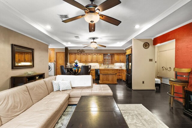 living area featuring dark wood finished floors, ceiling fan, washer / clothes dryer, and a raised ceiling