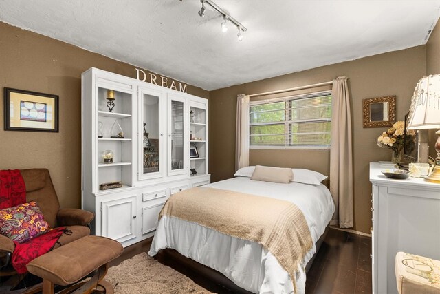 bedroom featuring track lighting and dark wood-style floors