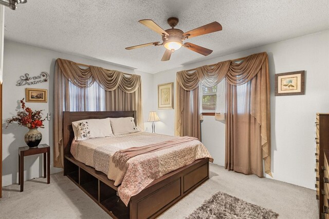 bedroom with a textured ceiling, a ceiling fan, and light colored carpet