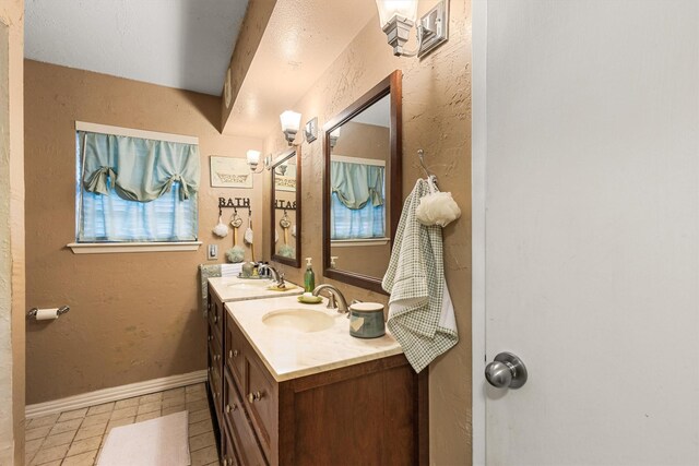 bathroom featuring double vanity, tile patterned floors, baseboards, and a sink