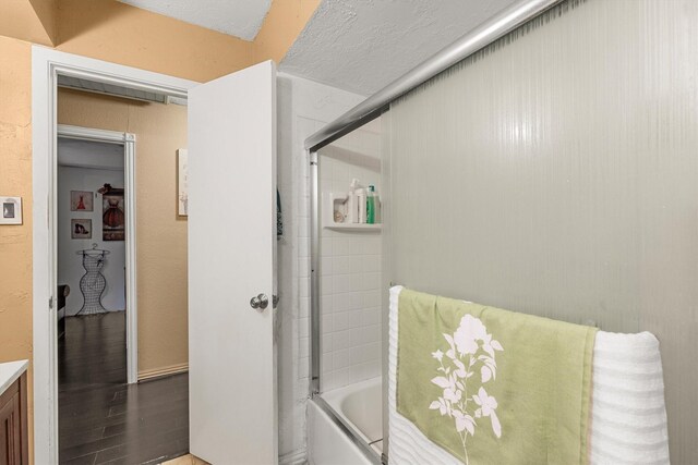 full bathroom featuring wood finished floors, vanity, and bath / shower combo with glass door