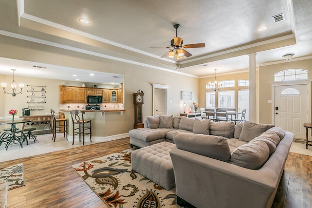 1944 Nottingham Dr, Kaufman, TX 75142 - living room with ceiling fan with notable chandelier, ornamental molding, a tray ceiling, and light wood-style floors