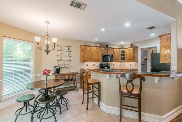 1944 Nottingham Dr, Kaufman, TX 75142 - kitchen featuring brown cabinets, visible vents, a breakfast bar area, and black appliances