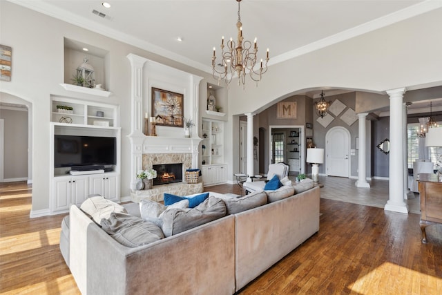 living area featuring a notable chandelier, baseboards, arched walkways, and built in shelves