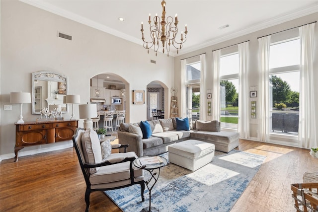 living room featuring wood finished floors, visible vents, arched walkways, and a notable chandelier