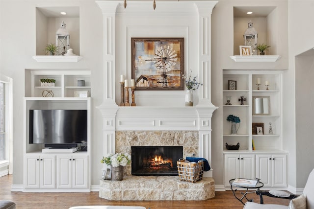 living room with a tiled fireplace, wood finished floors, and built in features