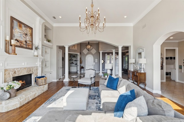 living area with built in shelves, arched walkways, wood finished floors, and decorative columns