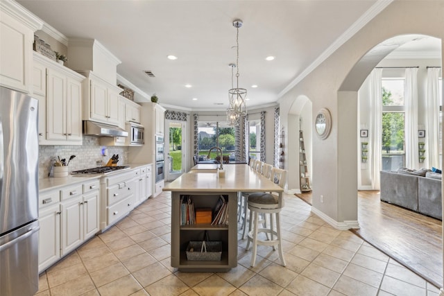 kitchen featuring arched walkways, stainless steel appliances, light countertops, and light tile patterned floors