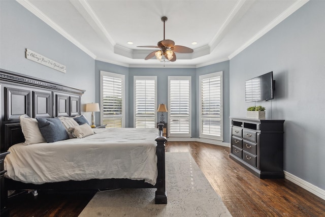 bedroom featuring wood finished floors, baseboards, a raised ceiling, and ornamental molding