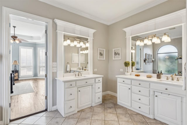 full bathroom featuring two vanities, ceiling fan, ornamental molding, and a sink