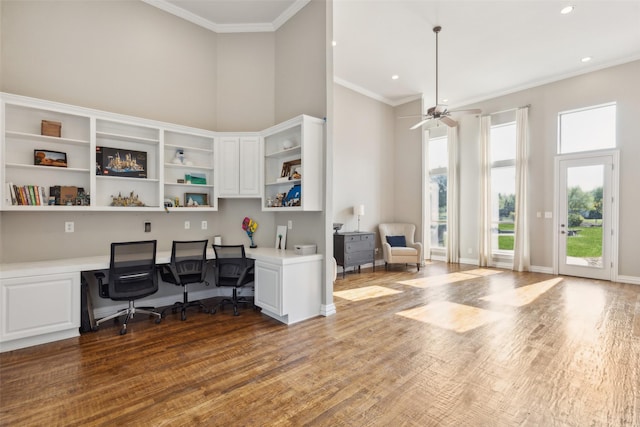 office space with built in desk, wood finished floors, ceiling fan, and ornamental molding