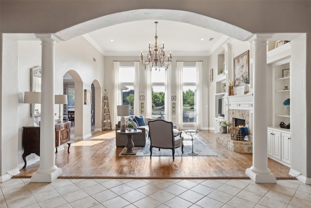 living room with light tile patterned flooring, crown molding, baseboards, a fireplace, and built in features