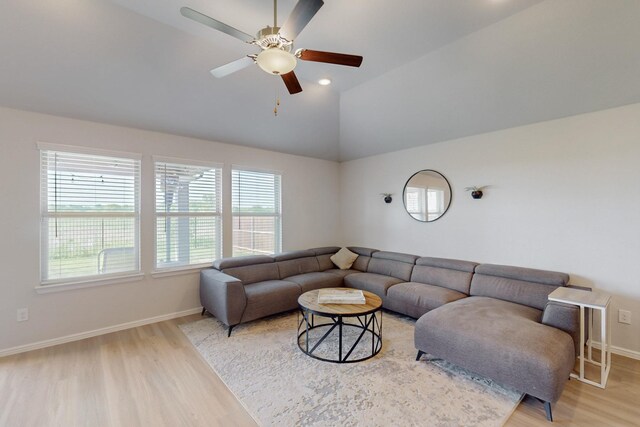 living area with vaulted ceiling, baseboards, light wood-style floors, and ceiling fan