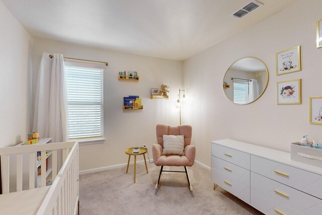 bedroom with a nursery area, light carpet, visible vents, and baseboards