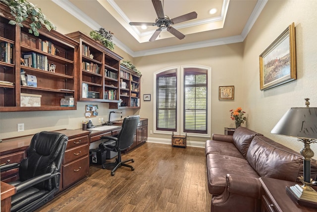 office area featuring a tray ceiling, dark wood finished floors, a ceiling fan, built in study area, and crown molding
