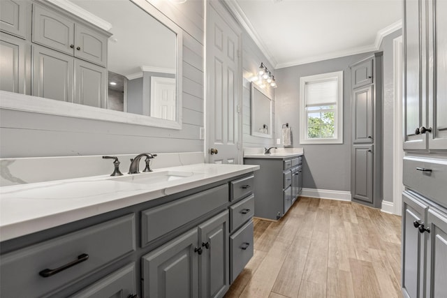 full bath featuring two vanities, baseboards, a sink, and ornamental molding