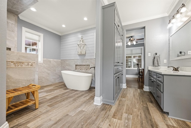 full bath with vanity, ornamental molding, a freestanding tub, and tile walls