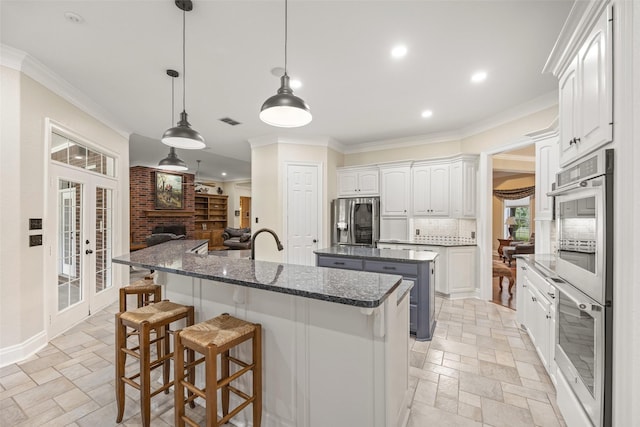 kitchen with stone tile flooring, recessed lighting, appliances with stainless steel finishes, and a center island with sink