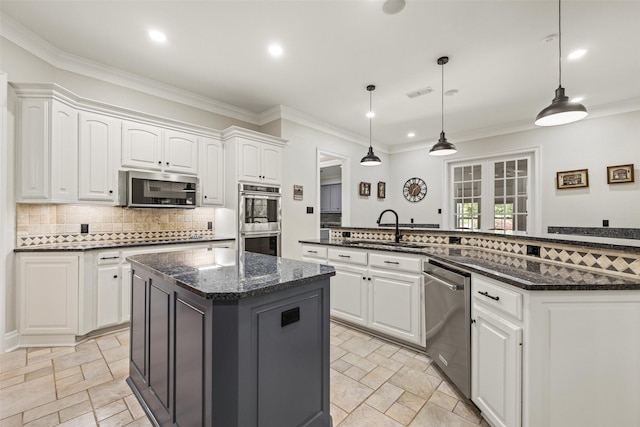 kitchen with tasteful backsplash, a sink, stone tile floors, appliances with stainless steel finishes, and a kitchen island