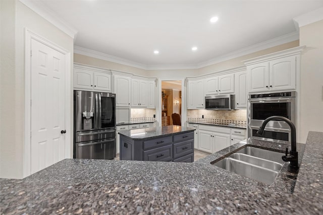 kitchen featuring backsplash, white cabinetry, stainless steel appliances, and a sink
